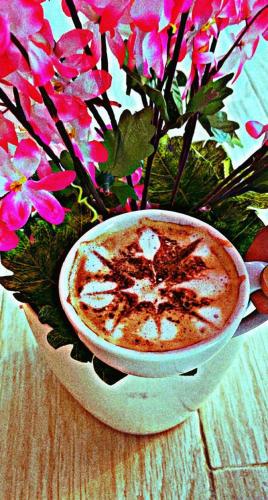 a cup of coffee in a bowl next to flowers at فندق ادوماتو ADOMATo HOTEl in Dawmat al Jandal