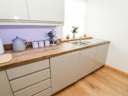 a kitchen with white cabinets and a wooden counter top at Flat Above 27 in Bishop Auckland