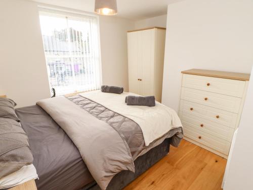 a bedroom with a bed and a dresser and a window at Flat Above 27 in Bishop Auckland