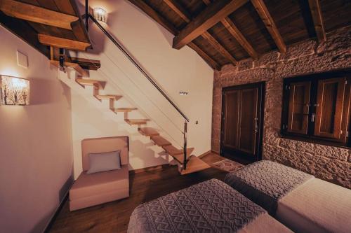 a bedroom with a staircase and a bed and a chair at Casa Rural Vilar de Flores in Ourense