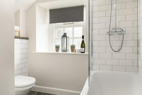 a white bathroom with a shower and a toilet at Bridge End Cottage in Stainforth