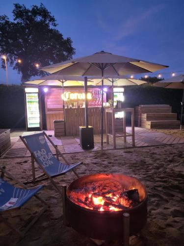 a fire pit in the sand with chairs and an umbrella at Swiss Army Camping Night / Militärbunker in Sankt Margrethen