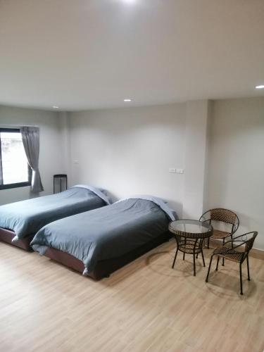 1 dormitorio con 2 camas, mesa y sillas en IHome Hatyai en Hat Yai