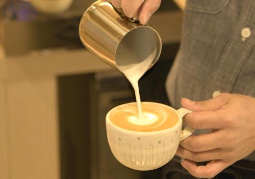 a person pouring coffee into a cup with a spoon at Oriental Hotel Fukuoka Hakata Station in Fukuoka
