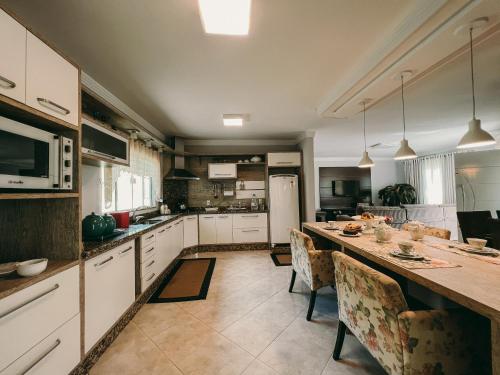 eine große Küche mit einem langen Tisch mit Stühlen in der Unterkunft Casa confortável em local tranquilo. in Rodeio