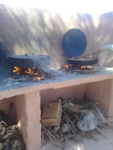 una estufa con dos ollas y sartenes en llamas en KONDUR ELEMENTOS ECO HOSTEL en Las Compuertas