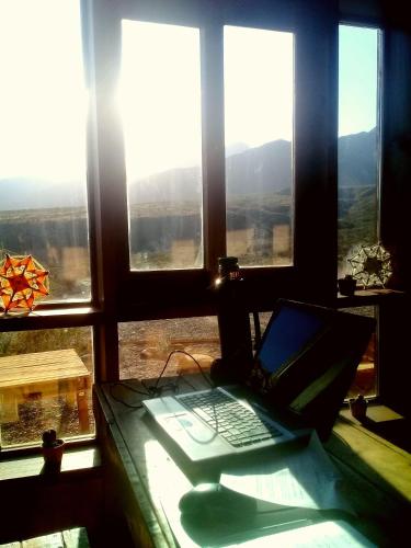 a laptop computer sitting on a desk in a room with windows at KONDUR ELEMENTOS ECO HOSTEL in Las Compuertas