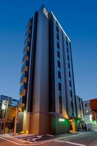 a tall building on a city street at night at Hotel Reference Reisen in Fukuoka