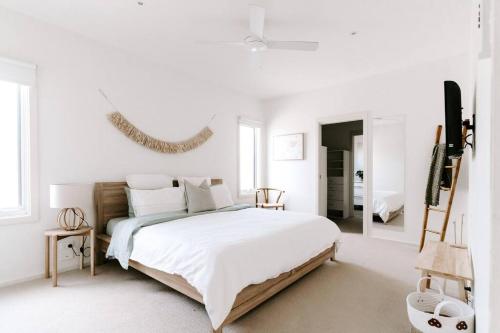 a white bedroom with a large bed and a mirror at Ocean Essence in Currarong