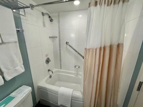 ホノルルにあるAla Moana Hotel 31st floorのバスルーム(白いバスタブ、シャワーカーテン付)
