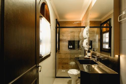 a bathroom with a sink and a toilet and a shower at Malbec Casa Hotel in Bento Gonçalves