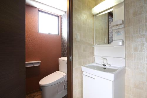 a bathroom with a toilet and a sink and a mirror at Hotel Japan Shiga in Yamanouchi