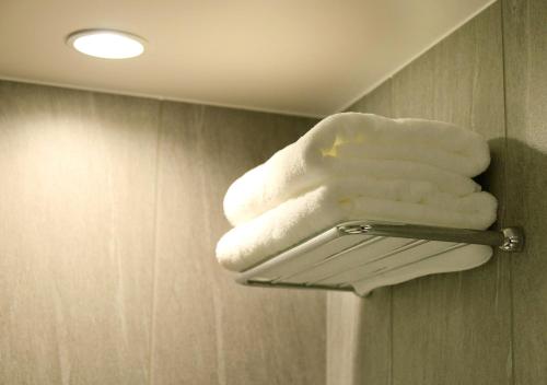 a pile of white towels on a towel rack in a bathroom at Oriental Hotel Fukuoka Hakata Station in Fukuoka