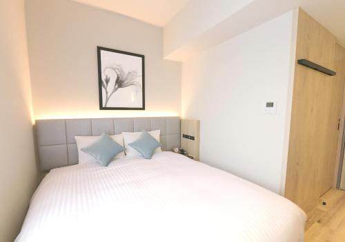 a bedroom with a white bed with blue pillows at Oriental Hotel Fukuoka Hakata Station in Fukuoka