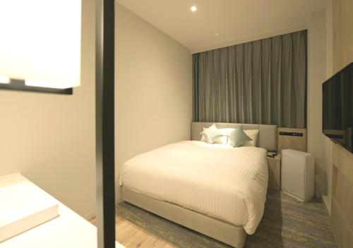 a bedroom with a bed with white sheets and pillows at Oriental Hotel Fukuoka Hakata Station in Fukuoka
