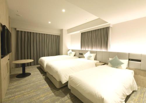 a hotel room with two beds and a table at Oriental Hotel Fukuoka Hakata Station in Fukuoka