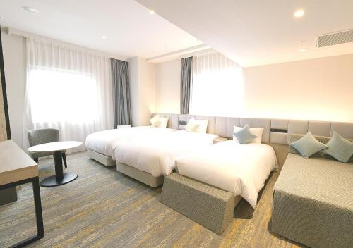 a hotel room with two beds and a couch at Oriental Hotel Fukuoka Hakata Station in Fukuoka