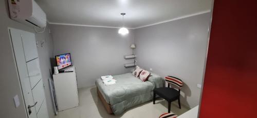 um pequeno quarto com uma cama e uma cadeira em Alquiler Céntrico Catamarca I em San Fernando del Valle de Catamarca