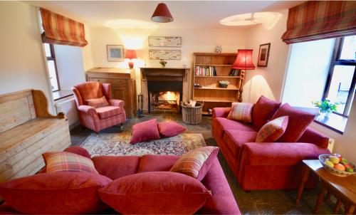 un soggiorno con mobili rossi e camino di Delphi Lodge Cottages a Leenaun