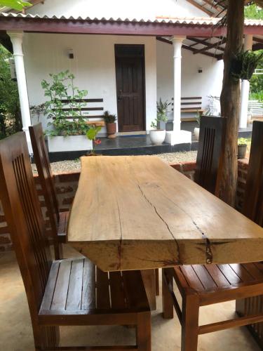 una mesa de madera y sillas frente a una casa en Sun Rise Family Resort - Anuradhapura, en Anuradhapura
