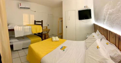 a small room with two beds and a tv at Pousada Beira Mar in Pitimbu
