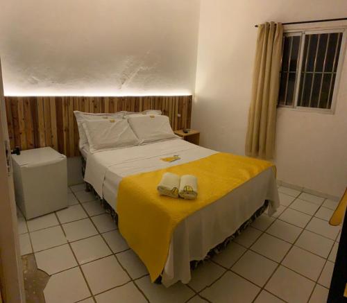 a bedroom with a bed with two shoes on it at Pousada Beira Mar in Pitimbu