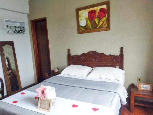 a bedroom with a bed and a picture of flowers at Pousada Santa Mônica in Divinópolis