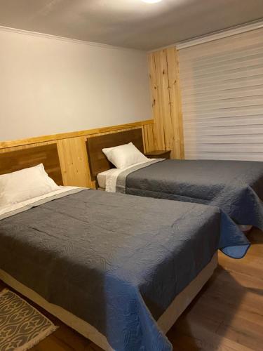 2 camas en un dormitorio con ventana en Rio Blanco en Hornopiren