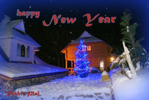 a blue christmas tree in the snow next to a cabin at Rakhiv Plai in Rakhiv