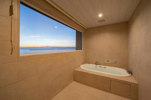 uma casa de banho com banheira e uma grande janela em GLAMPREMIER Setouchi em Kanonji