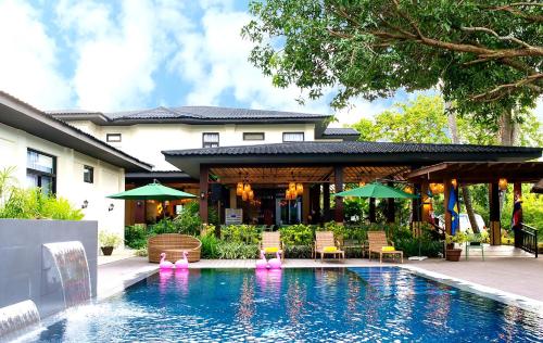 ドゥマゲテにあるUNWND Boutique Hotel Dumagueteの家の隣のスイミングプール(椅子、パラソル付)