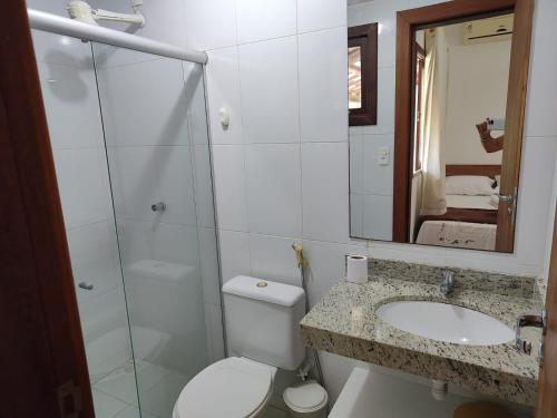 ein Badezimmer mit einem WC, einem Waschbecken und einem Spiegel in der Unterkunft Linda casa 4/4 com piscina na Praia do Forte. in Mata de Sao Joao