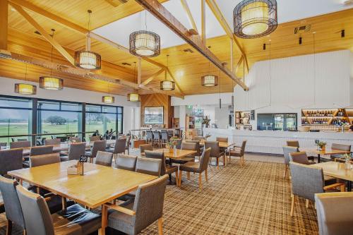 a restaurant with wooden ceilings and tables and chairs at 13th Beach Golf Lodges in Barwon Heads