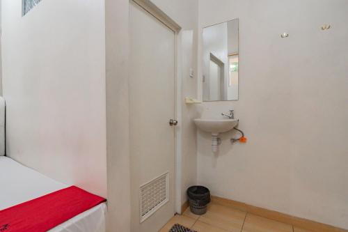 La salle de bains blanche est pourvue d'un lavabo et d'un miroir. dans l'établissement RedDoorz near Prujakan Station Cirebon, à Cirebon