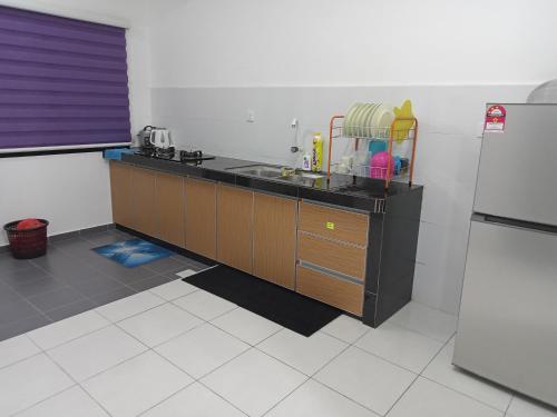 uma cozinha com um balcão com um lavatório e um frigorífico em Homestay UmahMak em Bandar Puncak Alam