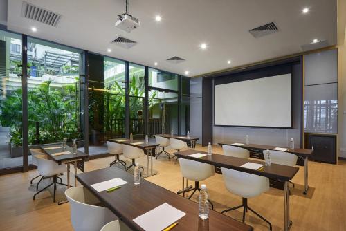 a conference room with tables and chairs and a projection screen at Hotel Komune Living & Wellness Kuala Lumpur in Kuala Lumpur