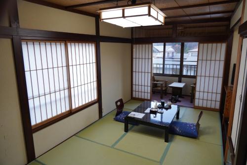 een kamer met ramen en een tafel en stoelen bij Oyado Eitaro in Takayama