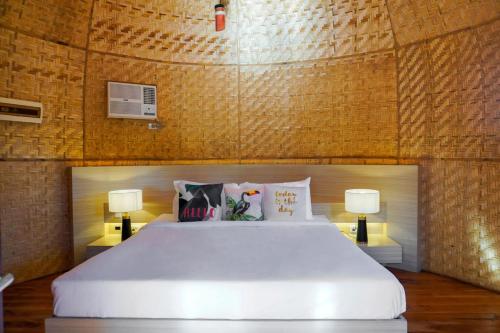a bedroom with a large white bed with two lamps at UNWND Boutique Hotel Dumaguete in Dumaguete
