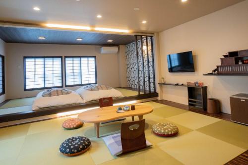 Habitación con 2 camas, mesa y TV. en Oyado Eitaro, en Takayama