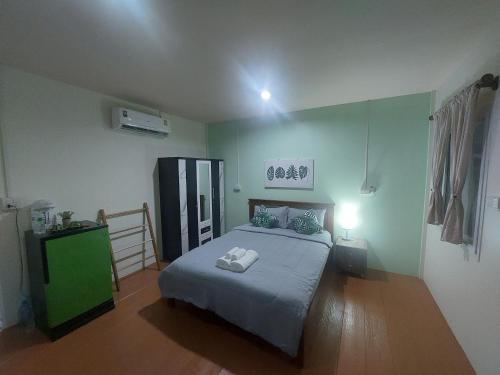 a bedroom with a bed and a green cabinet at Baan suan khun ta บ้านพักสวนคุณตา in Ko Chang