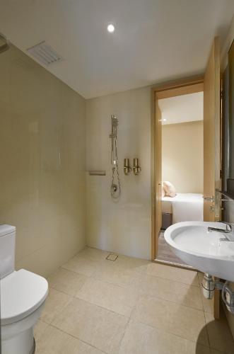 a bathroom with a toilet and a sink and a tub at Hotel Komune Living & Wellness Kuala Lumpur in Kuala Lumpur