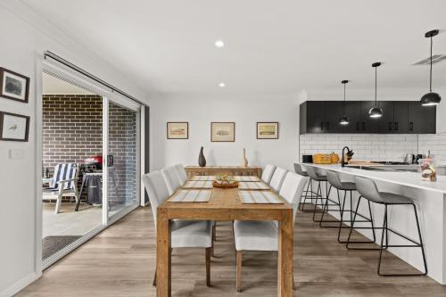 a kitchen and dining room with a wooden table and chairs at Libbity's at The Point by Experience Jervis Bay in Sanctuary Point