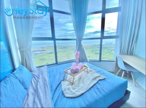 Cama azul en habitación con ventana en Atlantis Residences Melaka by HeyStay Management, en Melaka