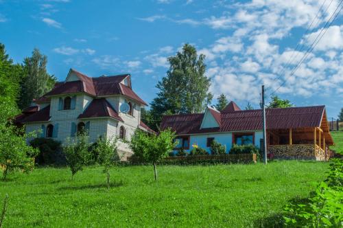 an old house with a clock on it in a field at Rakhiv Plai in Rakhiv