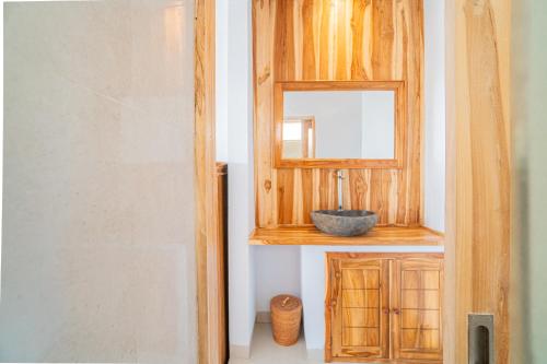 een badkamer met een houten kast en een spiegel bij Sekar Penida Cottages in Nusa Penida