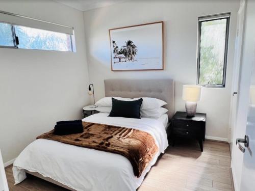 um quarto branco com uma cama grande e 2 janelas em Tranquil Tree Views 2 Bedroom 2 Bathroom Apartment em Perth