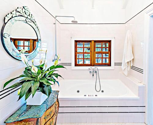a white bathroom with a tub and a mirror at Tranquilo Beach House in Woolgoolga
