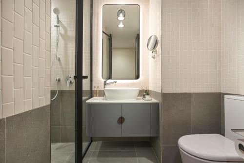 a bathroom with a sink and a mirror and a toilet at Citadines Connect Rochester Singapore in Singapore