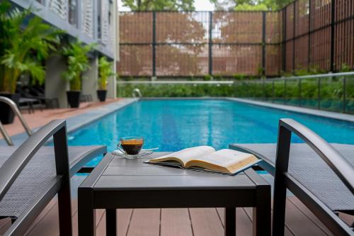 a table with a book and a drink on it next to a pool at SILA Urban Living in Ho Chi Minh City