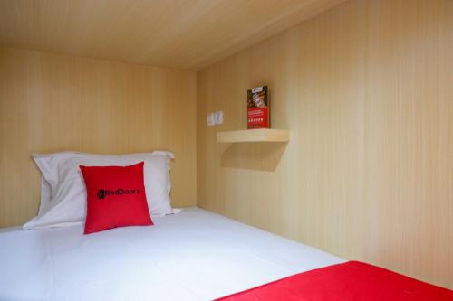 a bedroom with a red pillow on a bed at RedDoorz Hostel near Lawang Sewu Semarang in Kalibanteng-lor